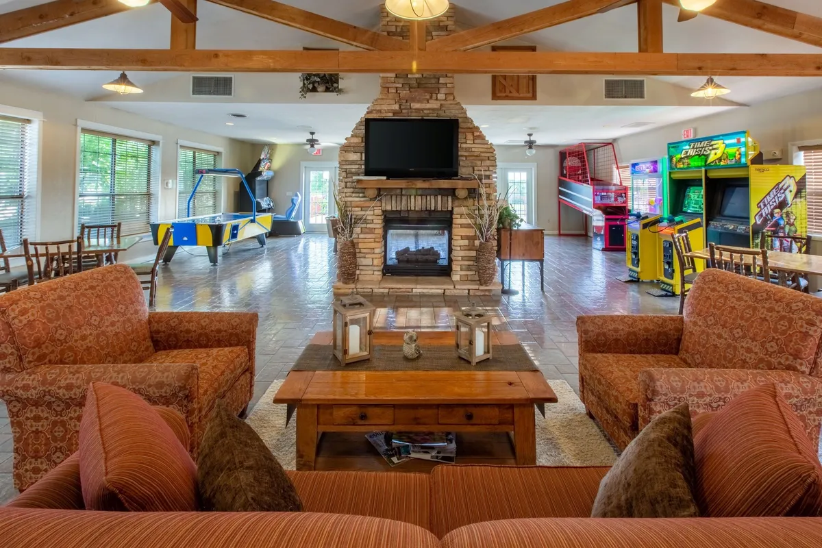 An inviting indoor space featuring a fireplace, a well-equipped game area, and comfortable seating. People are seen gathered around game tables, creating a vibrant and social environment ideal for families and groups to enjoy activities like board games, cards, or simply relaxing together.