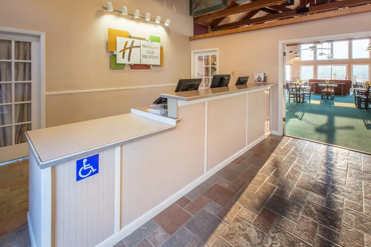 This interior image captures the reception desk with the recognizable Holiday Inn logo, and a dining area visible in the background. The scene showcases guests checking in and socializing, hinting at communal conveniences and the friendly, lively atmosphere of the resort's shared spaces.