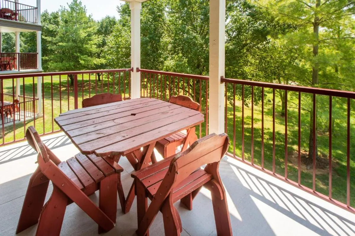 An inviting outdoor dining area featuring wooden tables and chairs surrounded by lush greenery, suggesting a relaxed setting for enjoying casual meals or unwinding with friends and family. The scene radiates comfort and ease, with a casual, sociable ambiance.